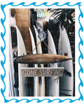 Gone Surfing rustic wooden surfboard sign with blue wave border frame and surfboards in background
